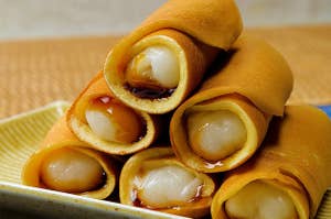 皿に盛られたクレープに包まれたクリーム入りロールケーキ。