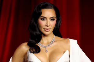 Kim Kardashian posing in a corset and draped coat on a red carpet