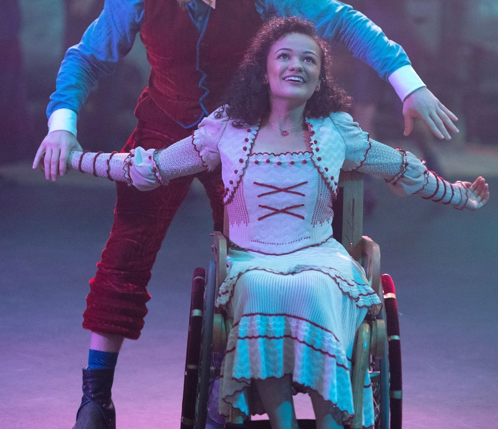 Nessarose in a detailed blouse and skirt, dancing with Boq