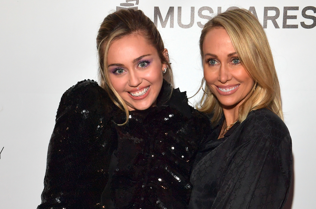 Miley Cyrus and Tish Cyrus posing together on the red carpet, both wearing elegant black outfits