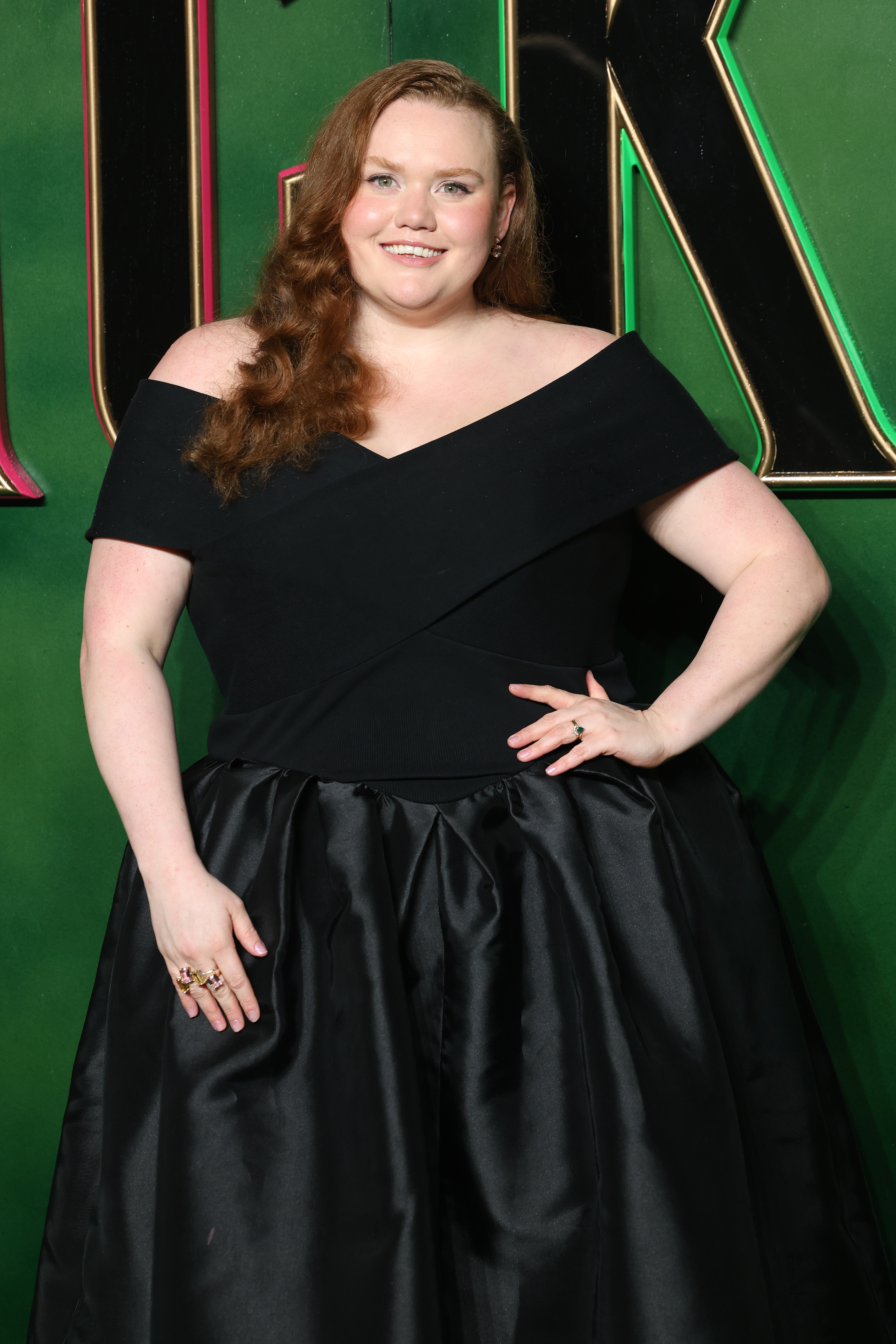 Bronwyn in an elegant off-shoulder black gown posing on a red carpet