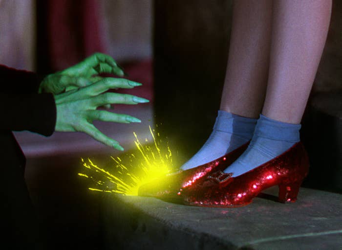 A pair of feet in glittering shoes, approached by green hands, sparking with yellow light, reminiscent of a classic movie scene