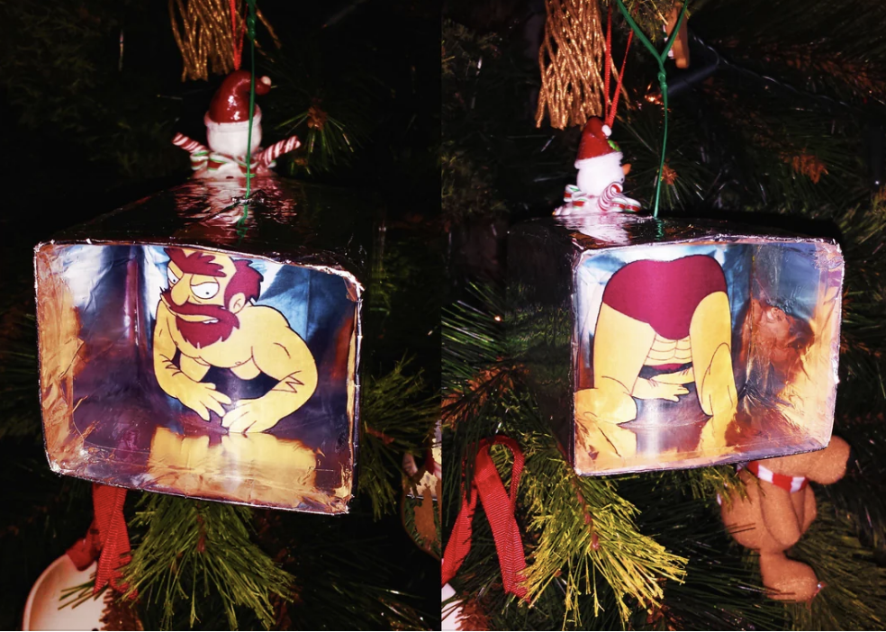 Christmas tree ornament featuring a humorous, reversible cartoon figure with a grumpy expression on one side and a rear view on the other