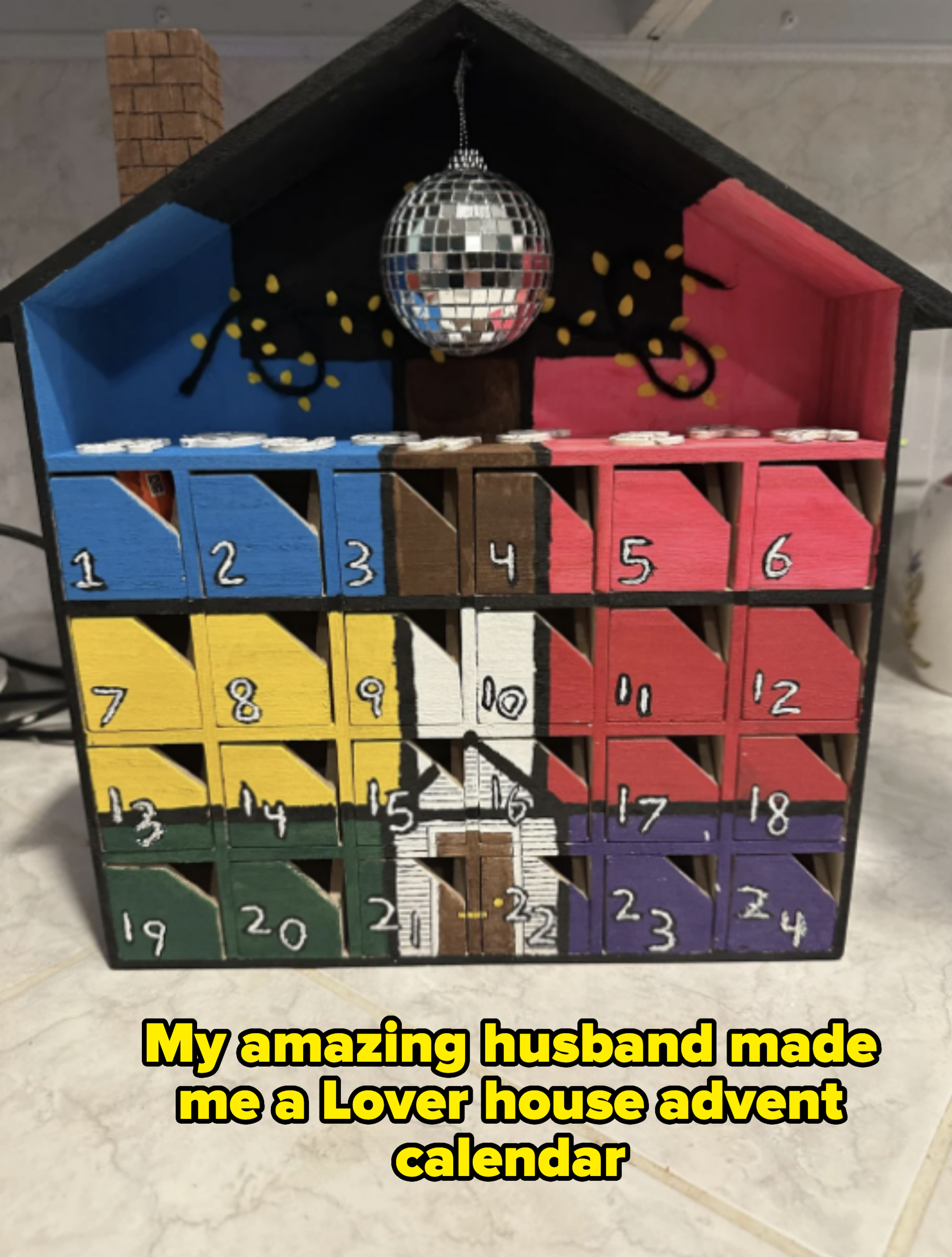 Advent calendar shaped like a house with numbered doors, a disco ball decoration on top, and festive accents