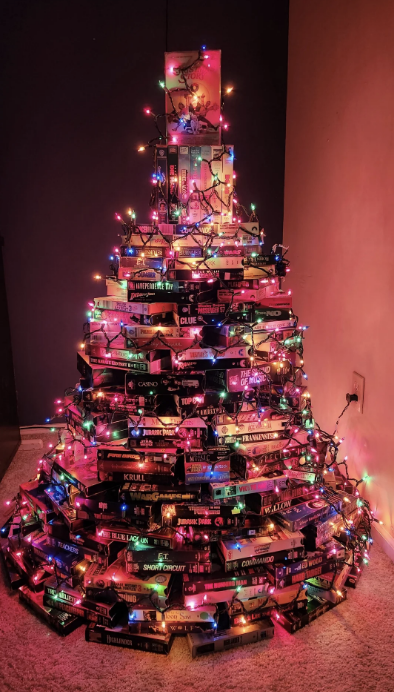 A Christmas tree made of stacked video game boxes, wrapped in colorful lights, topped with a small poster of The Legend of Zelda: Breath of the Wild