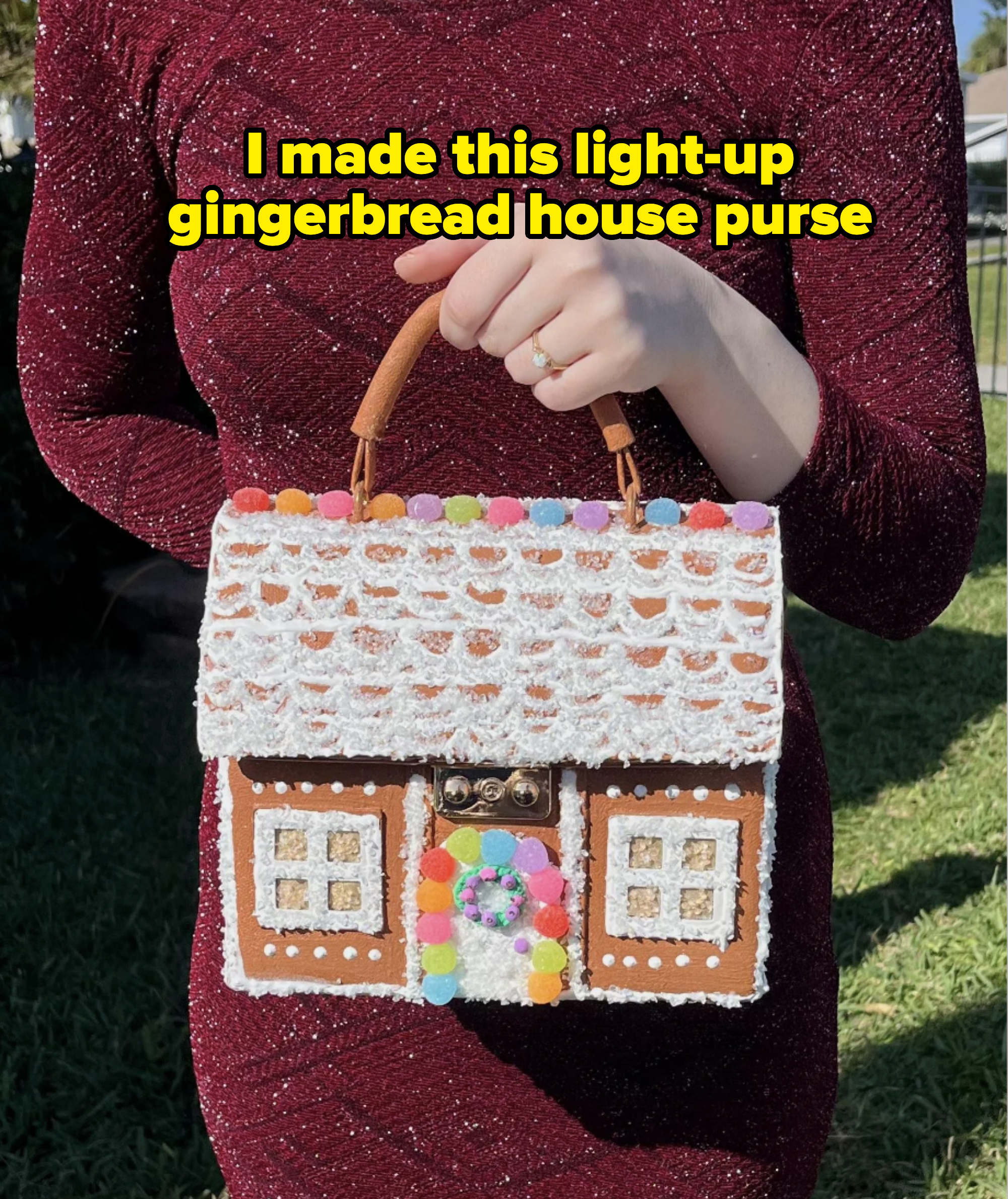 Person holding a handbag styled like a gingerbread house, wearing an elegant textured dress