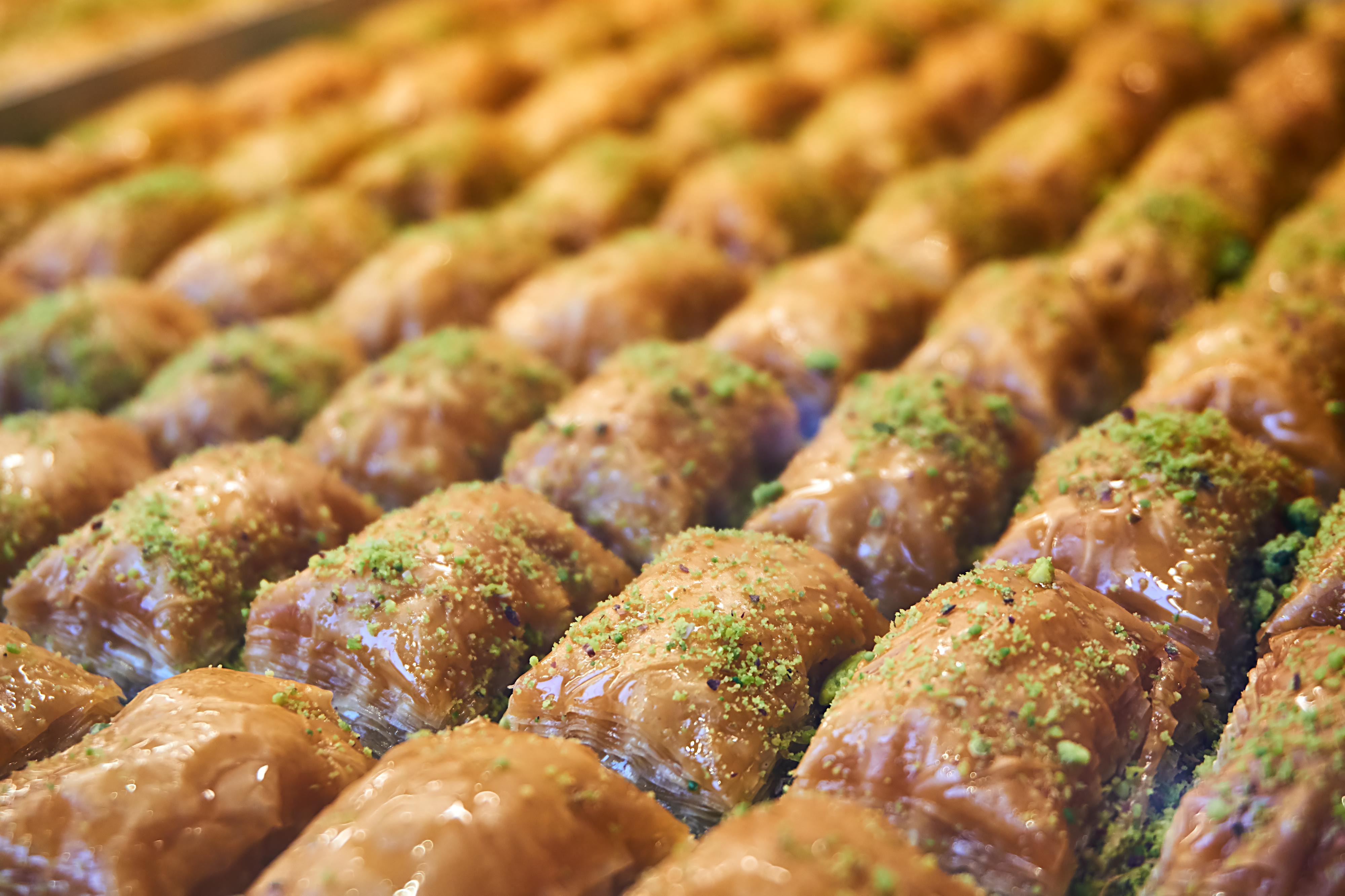 Rows of baklava topped with crushed nuts on display.