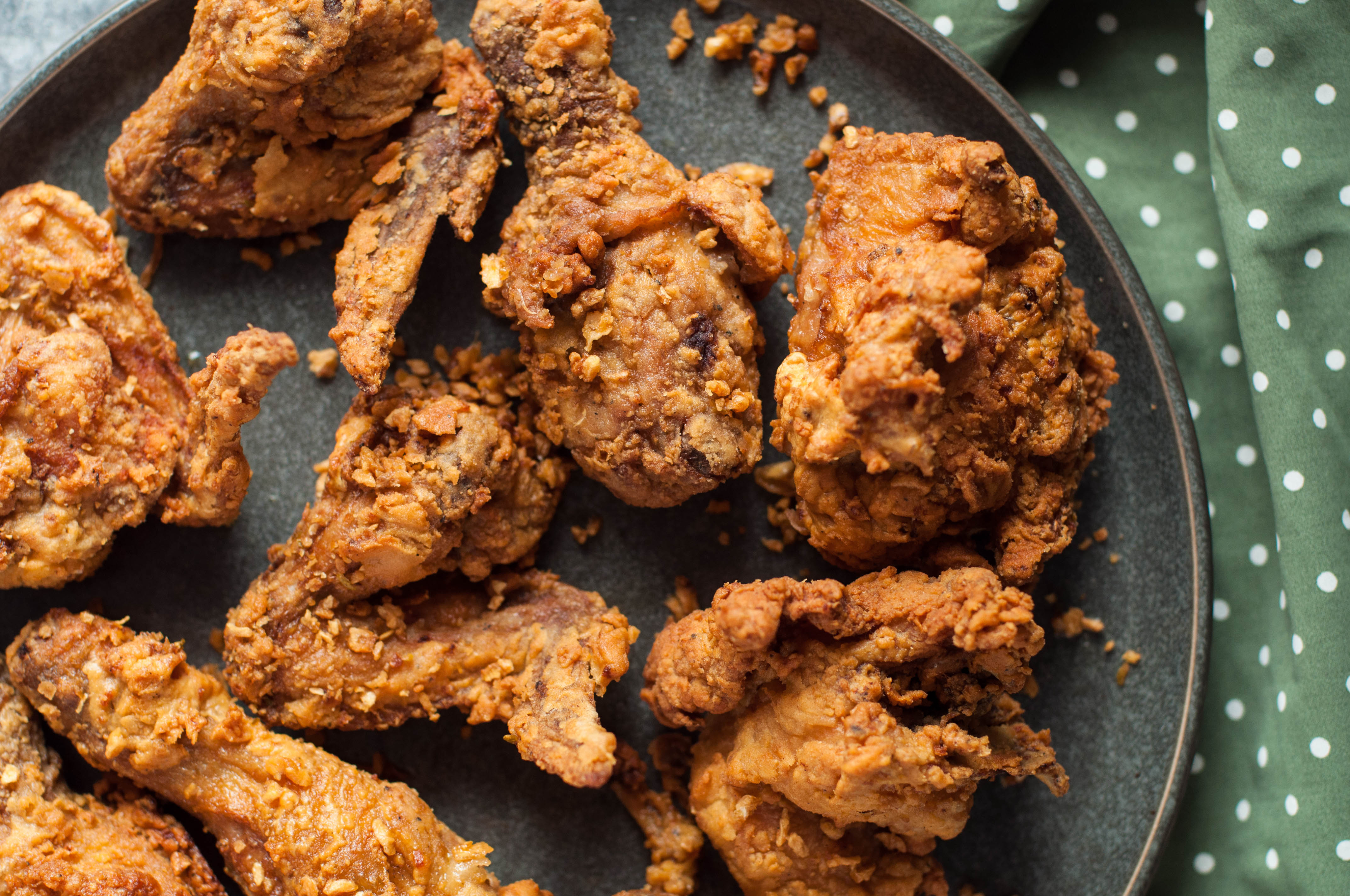 A plate of crispy fried chicken pieces arranged on a dark dish.