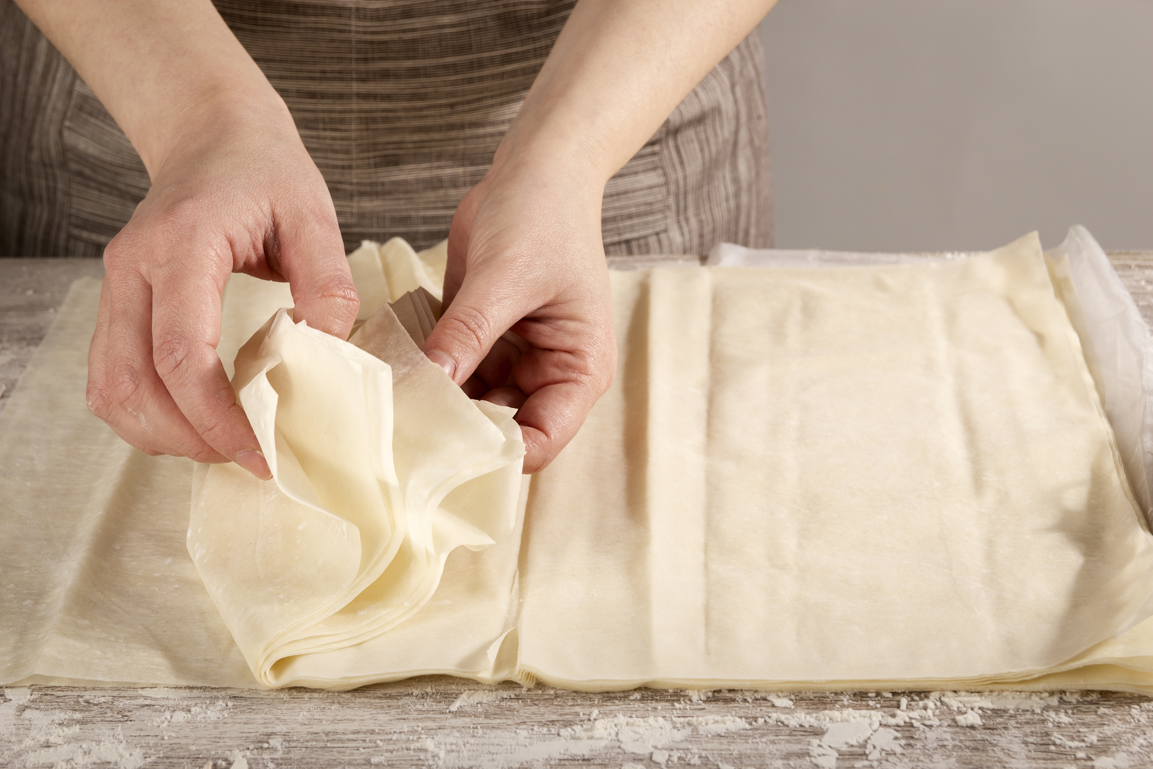 Hands holding sheets of dough.