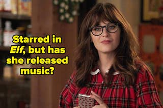 Person with glasses holding a phone, wearing a plaid shirt with a collar, indoors