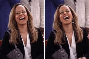 Person laughing joyfully, wearing a black blazer and white top, holding a handbag