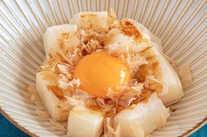 卵黄が中央に置かれた餅と鰹節の盛り付け。