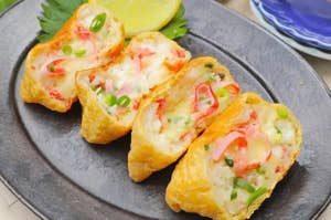 お皿に盛られたカニサラダを詰めた揚げ物料理。薬味が添えられ、レモンが添えられている。