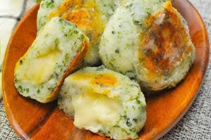 木の皿に乗ったチーズ入りのポテト団子が数個あります。