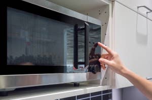 電子レンジのドアを開けようとしている手。