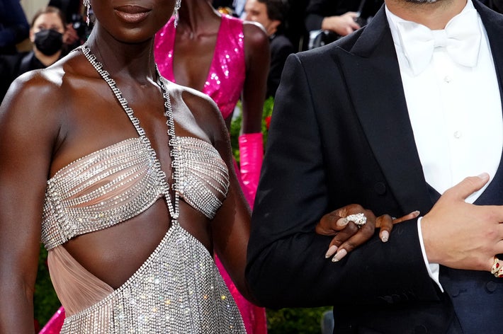 Jodie Turner-Smith and Joshua Jackson on a red carpet event; one wearing a shimmering gown and the other in a tuxedo, amidst photographers and attendees