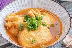 豆腐のお吸い物風スープに、刻んだネギがトッピングされている料理の写真。器には汁と豆腐が盛り付けられている。