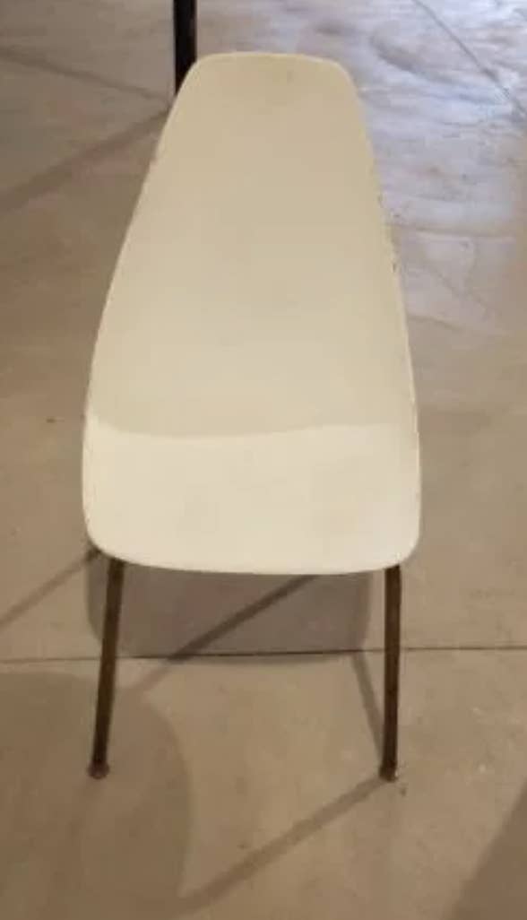 Simple, modern chair with a curved backrest and metal legs, viewed from the front