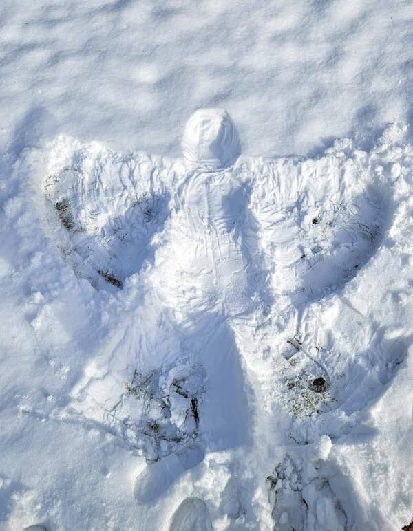 Snow angel imprint in fresh snow, showing outstretched wings and body shape