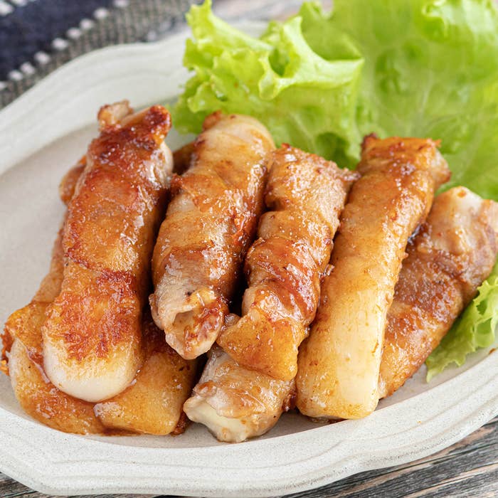 お皿に盛られた、焼かれた豚バラ肉の野菜巻きが載っている料理。レタスが添えられている。