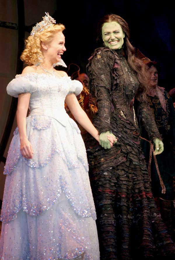 Kristin and Idina holding hands and smiling during the final bows for Wicked