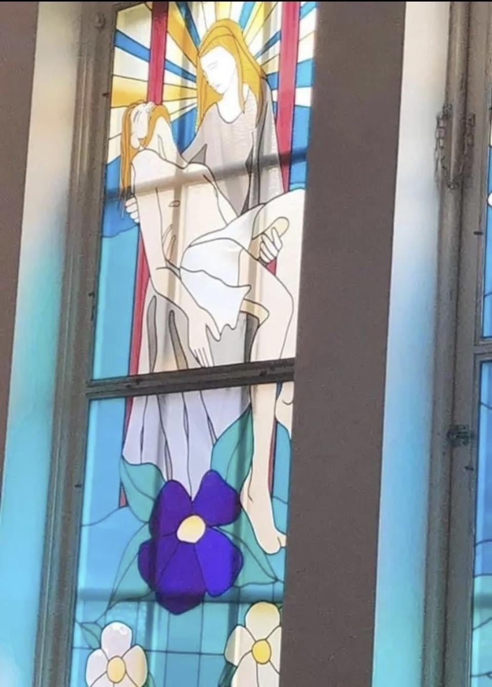 Stained glass window depicting a serene religious scene with two figures and floral elements