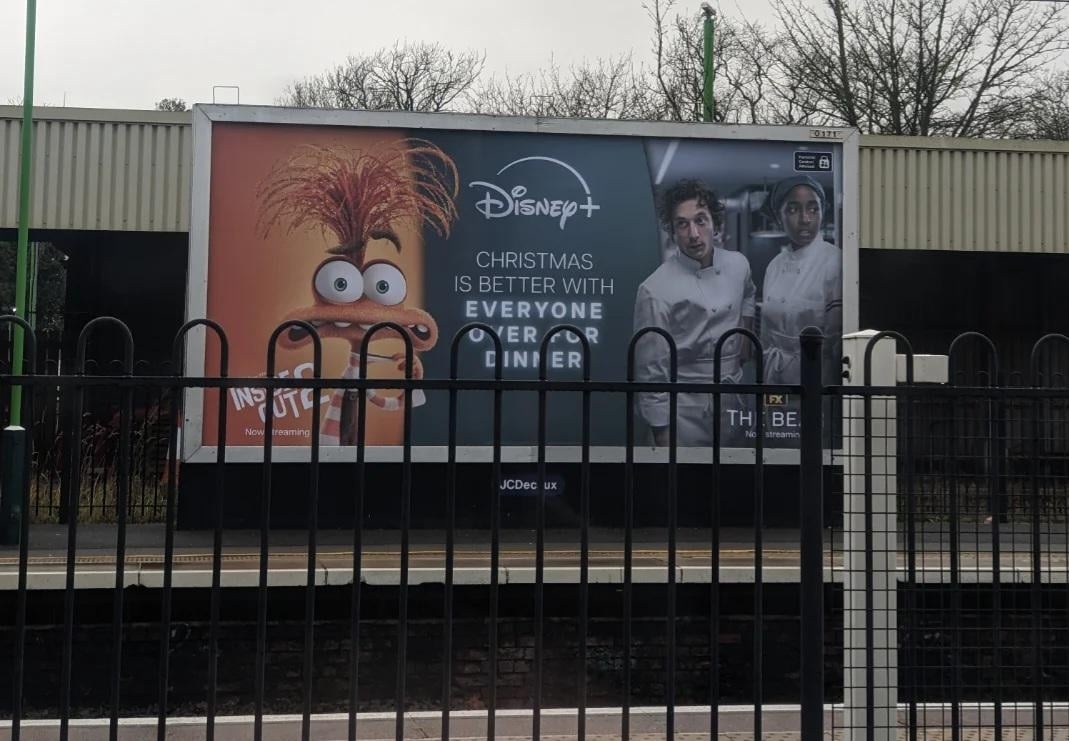 Billboard ad for Disney+ featuring animated characters and chefs, promoting a Christmas theme with the slogan, "Christmas is Better with Everyone."