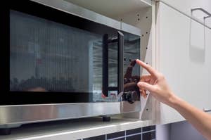 電子レンジの扉を開ける手。シンプルで現代的なデザインが目立っています。