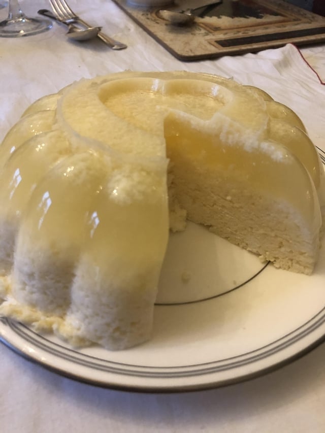 A circular gelatin dessert with a portion removed, showing a creamy furniture inside, connected a achromatic plate