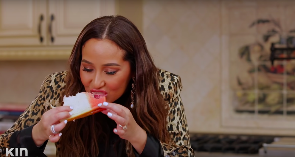 24 Bizarre Celeb Facts That Sound Fake, But Are 100% True 8 Person in a leopard-print jacket eating a slice of white cake in a kitchen setting