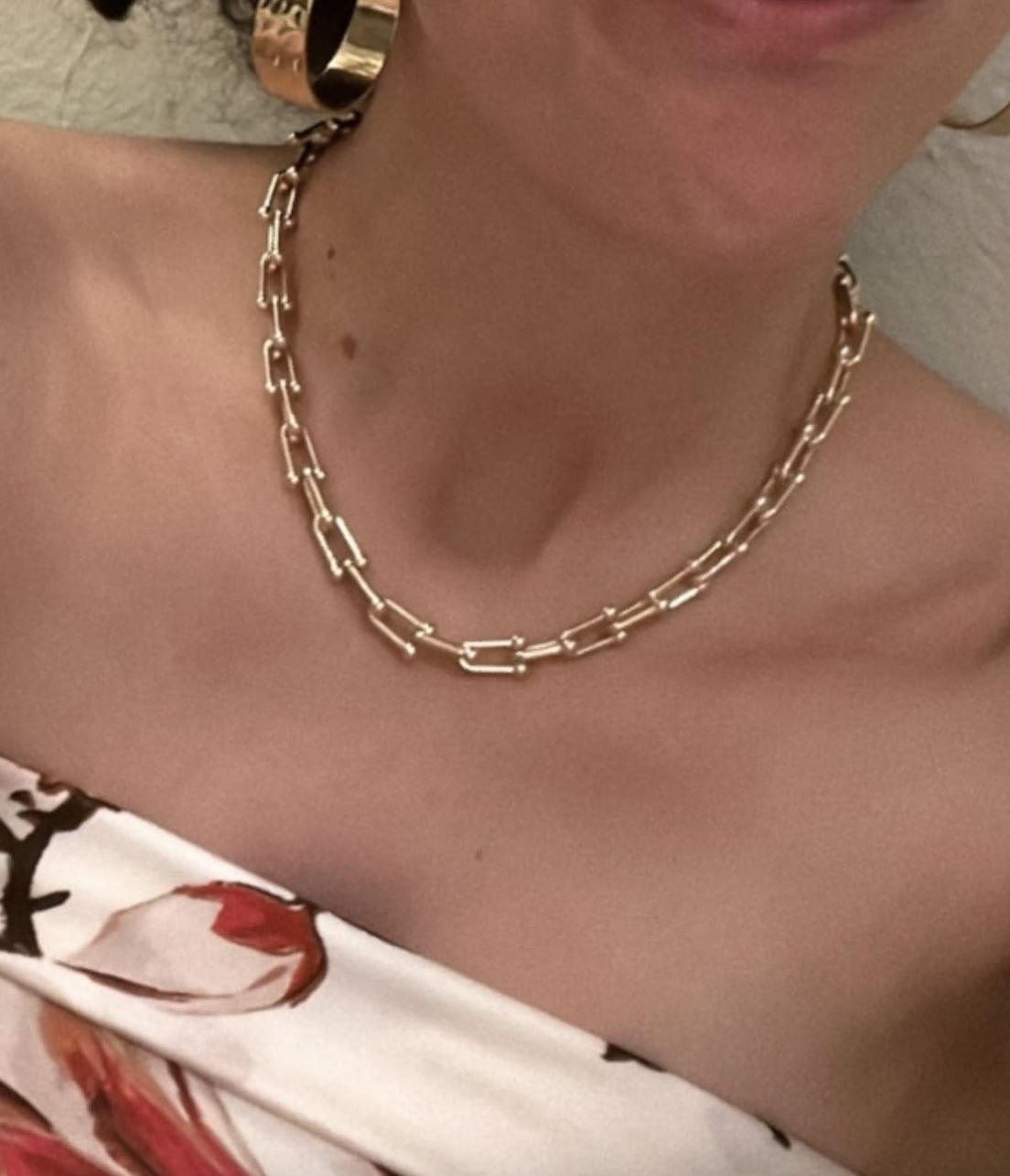 Person wearing a strapless floral top with a gold chain necklace and large hoop earrings