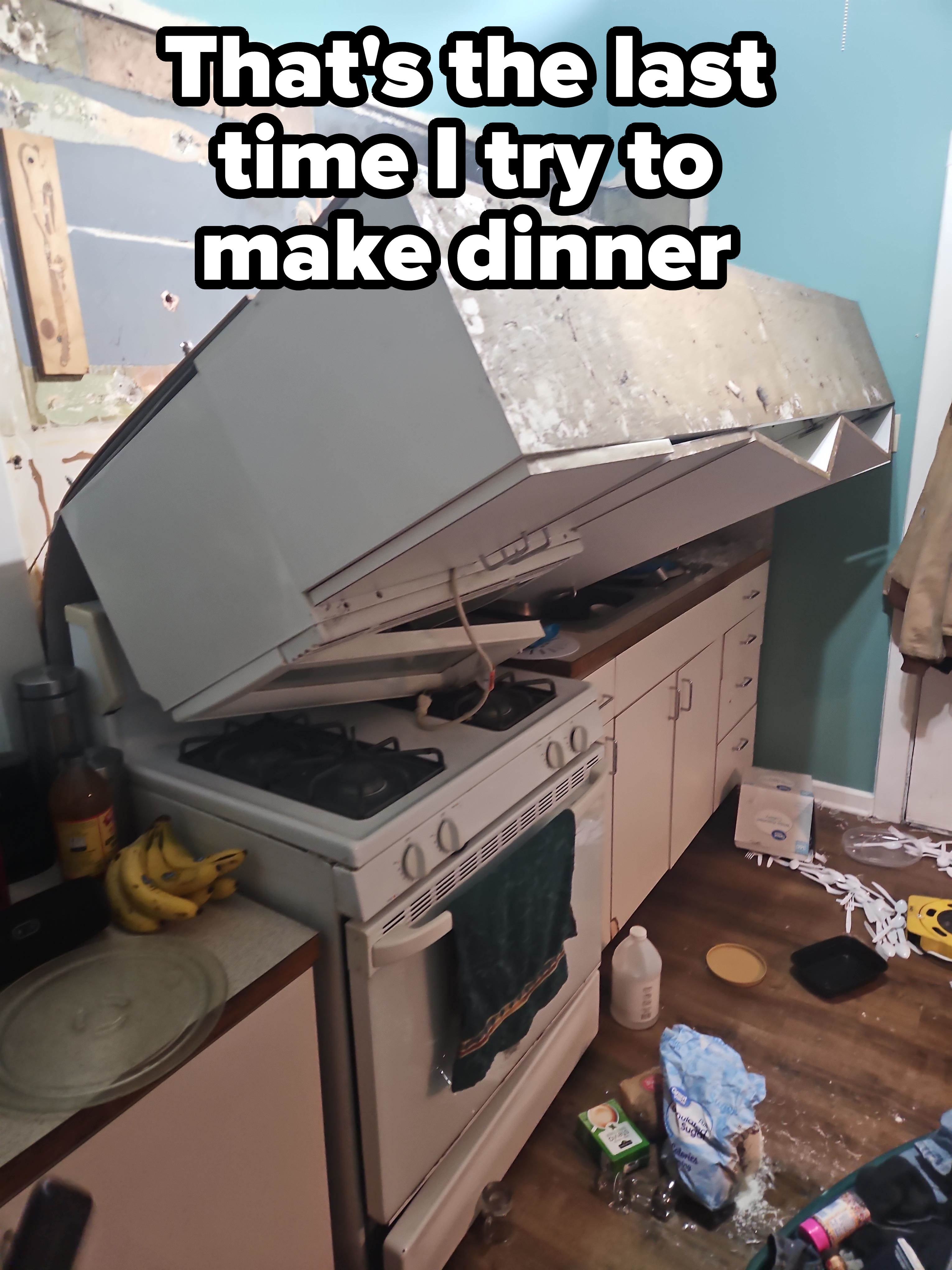 Kitchen disaster with a wall cabinet collapsed over a stove, displacing items and causing a mess on the floor