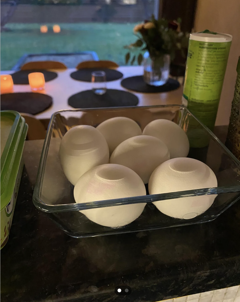 Eggs in a glass dish on a counter, with a view of candles and a window in the background