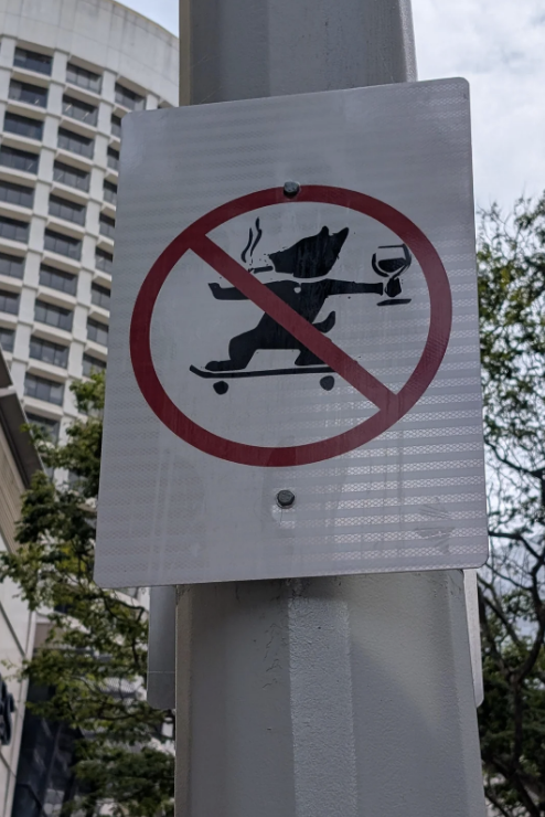Sign with crossed-out icon of a bear skateboarding, holding a glass and cigarette, indicating prohibition