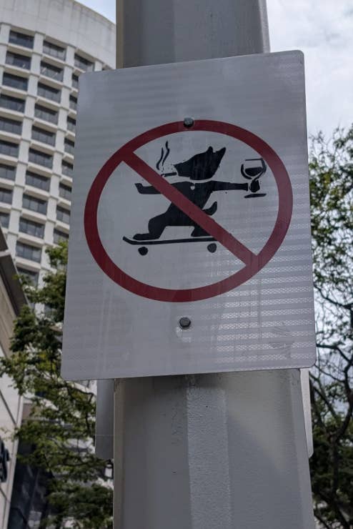 Sign with crossed-out icon of a bear skateboarding, holding a glass and cigarette, indicating prohibition