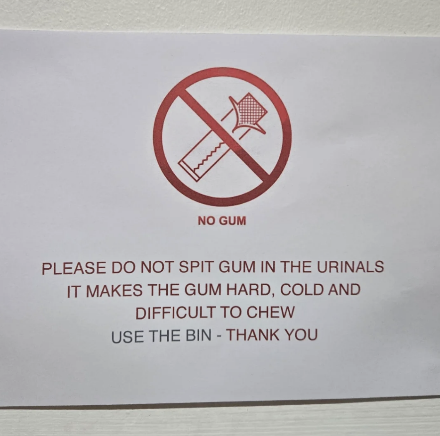 Sign with red crossed-out gum graphic. Text: "Do not spit gum in urinals. Gum becomes hard, cold, and difficult to chew. Use bin."