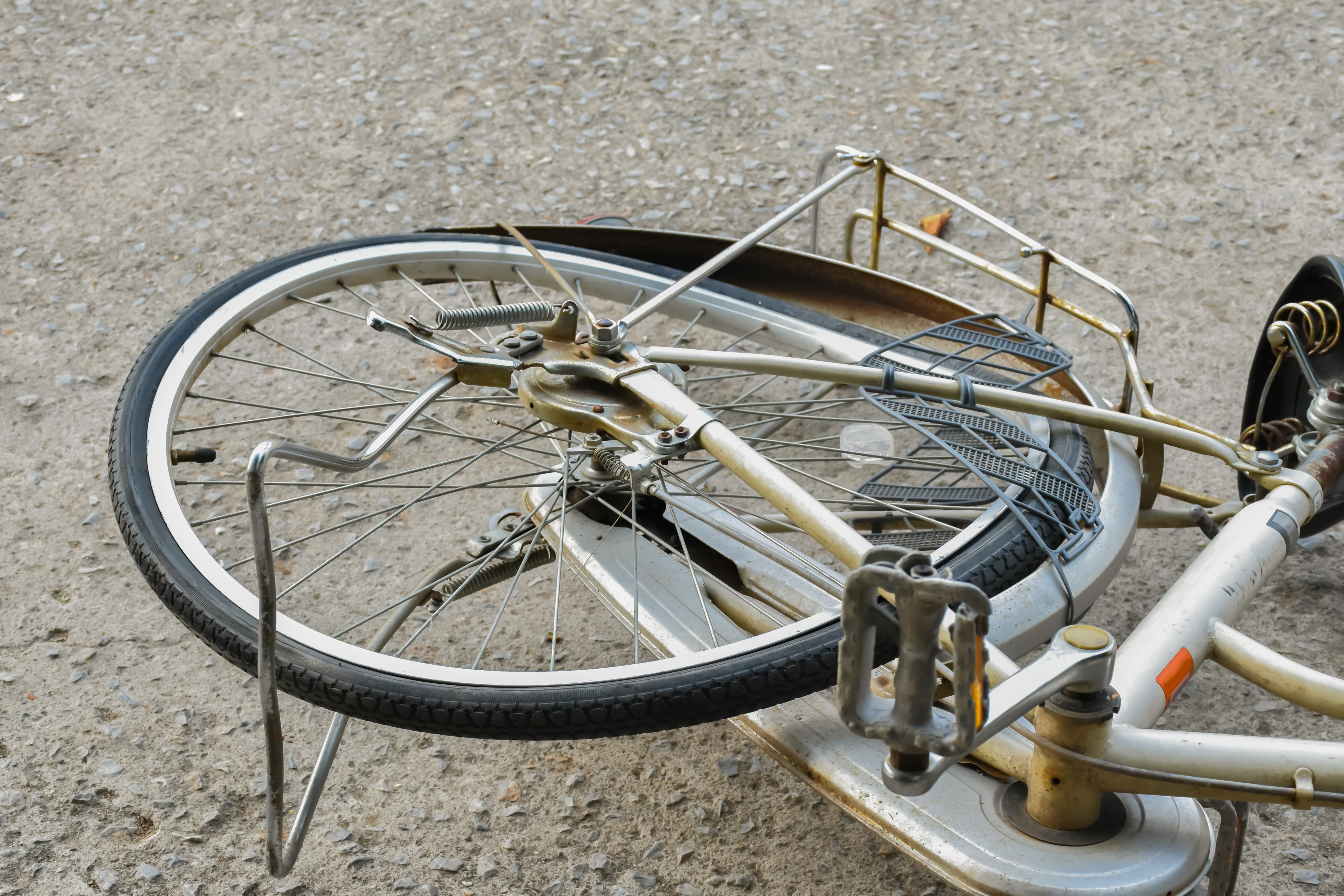 Bicycle on the ground with a bent rear wheel and damaged frame, suggesting it has been involved in an accident or fall