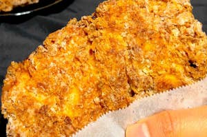 手で持たれたフライドチキンのクローズアップ。食欲をそそるクリスピーな食感が特徴。