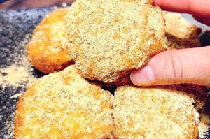 手で持っているきな粉をまぶした揚げ菓子のクローズアップ。