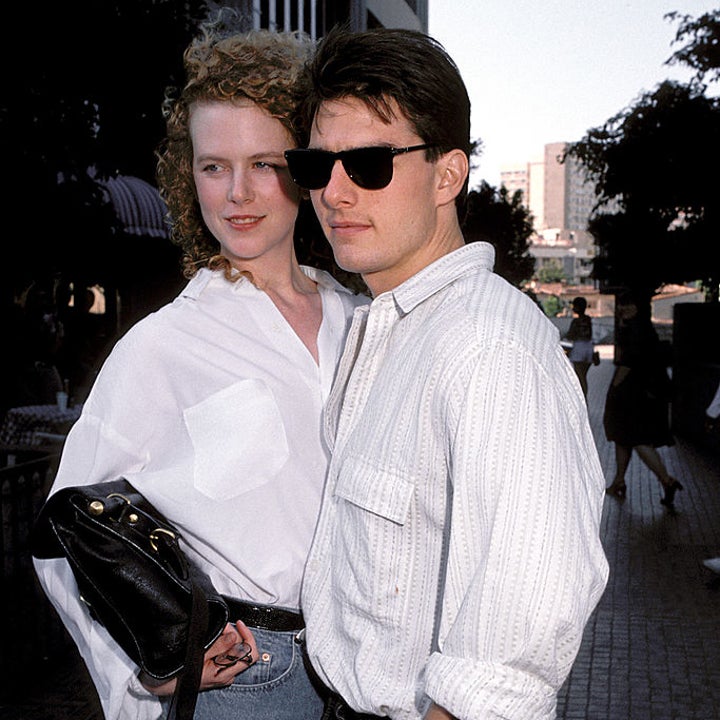 A celebrity couple poses together outdoors, both wearing casual outfits with sunglasses. The person on the right wears a white shirt and rolled-up sleeves