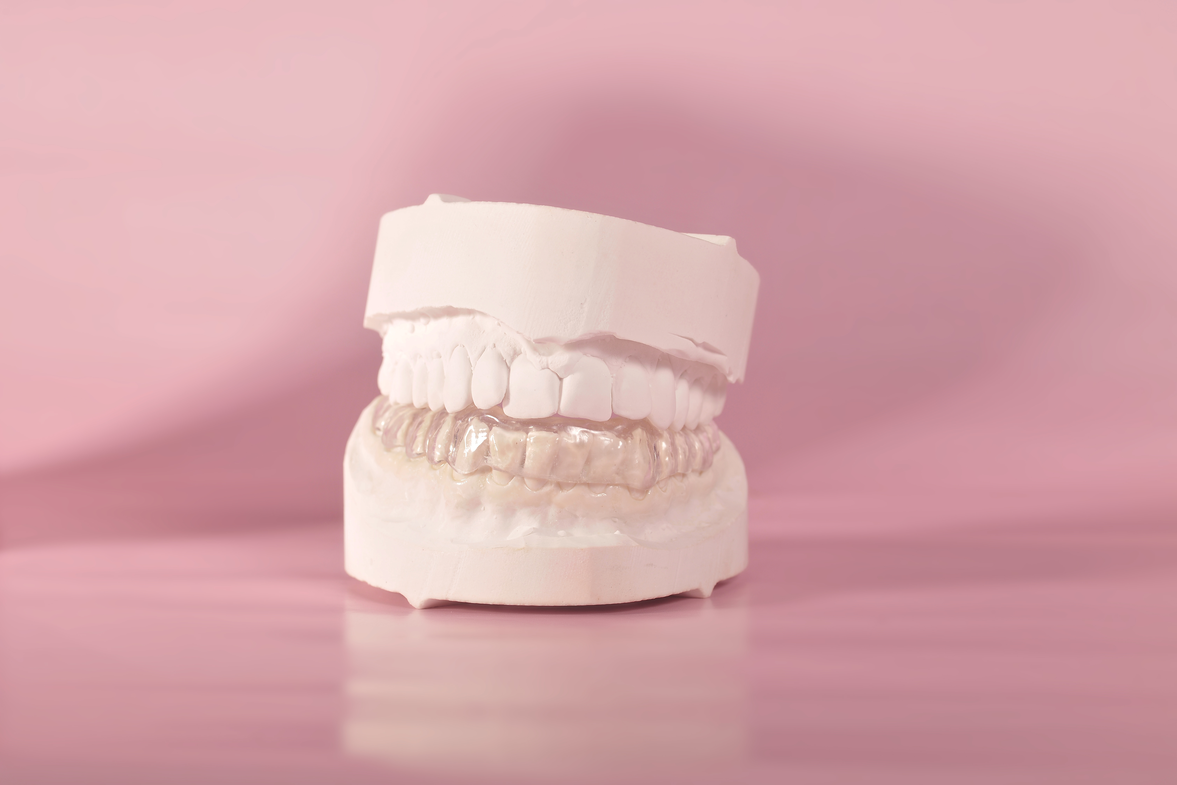 Dental model of teeth on a pink background, used to illustrate oral health or dental care topics