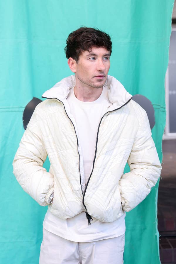 Barry Keoghan in a quilted jacket and casual outfit standing against a plain backdrop, looking to the side