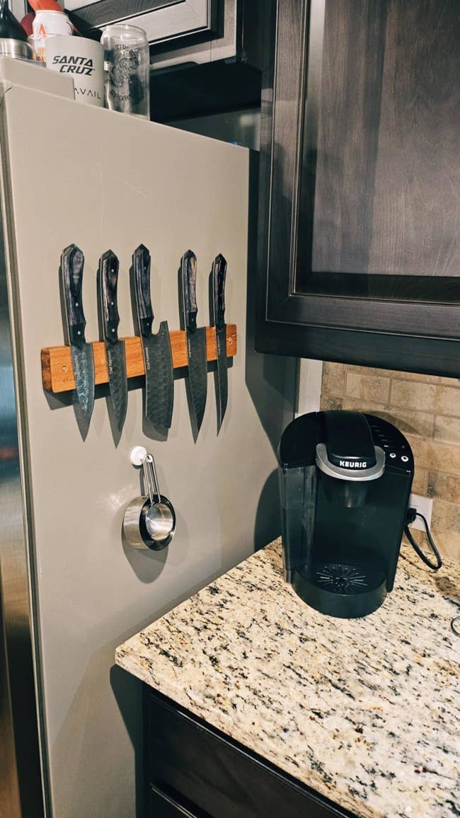 Kitchen countertop with a Keurig java shaper and a magnetic weapon holder displaying 5 room knives connected the broadside of a fridge
