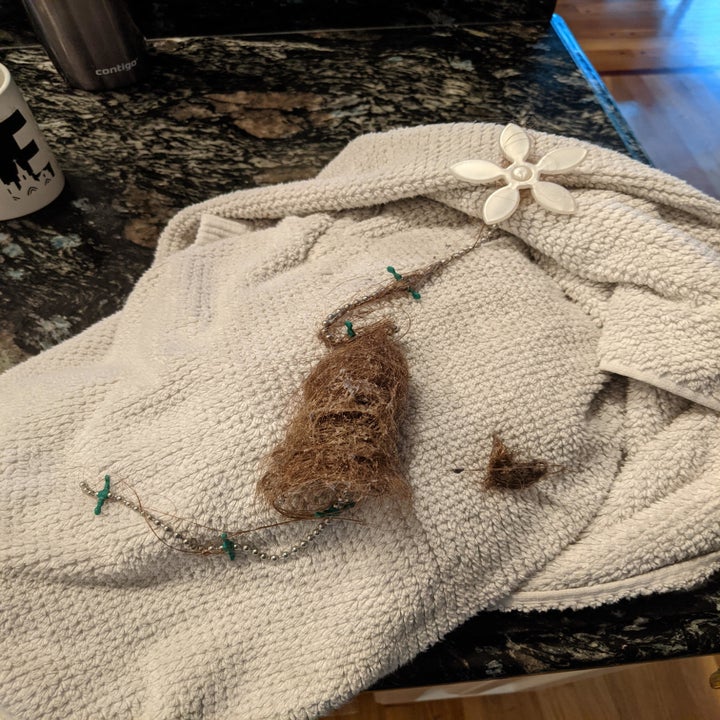 A clump of hair wrapped in a string of green mini-lights and a white floral clip placed on a towel on a kitchen counter