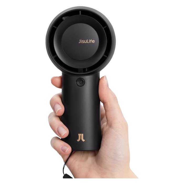 Hand holding a portable Jisulife fan, showcasing its compact design suitable for easy transport and personal use