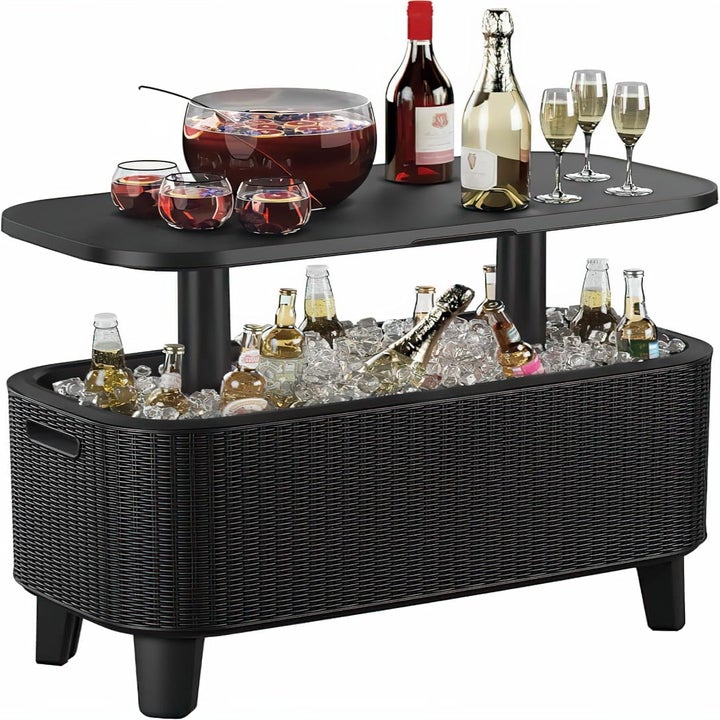 Black outdoor bar cart with ice-filled cooler, various beverages, and a punch bowl with drinks on the top shelf; featured in a shopping article