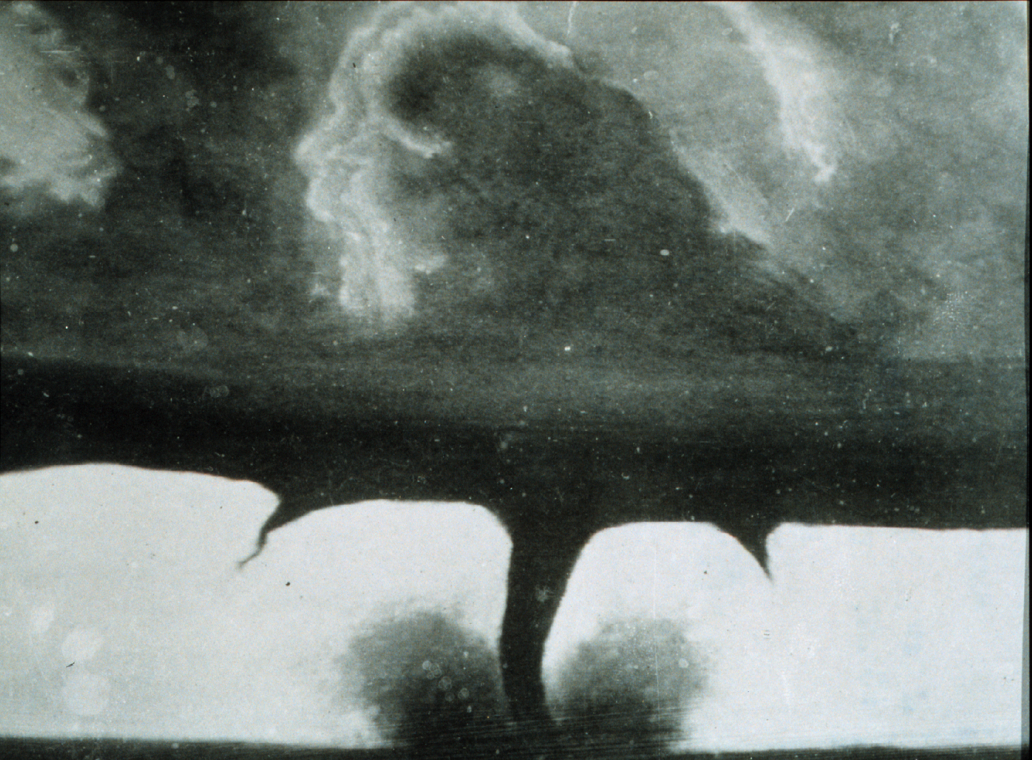 Historic black and white photo of a tornado touching down from a stormy sky