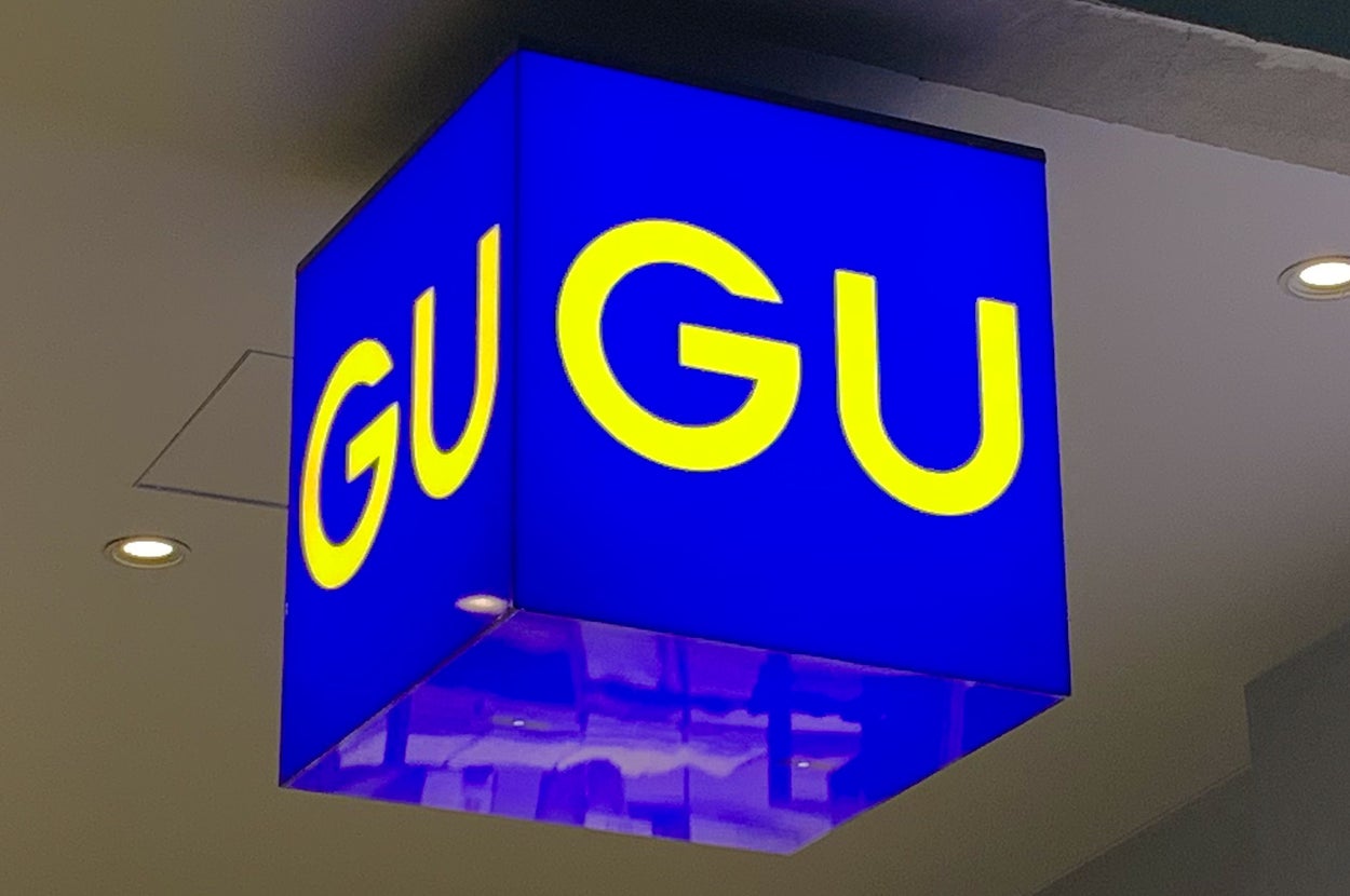 Blue cube-shaped store sign with yellow "GU" lettering hanging from the ceiling