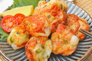 皿に盛られた揚げた海老と野菜の天ぷら、レモンとミニトマトを添えて。