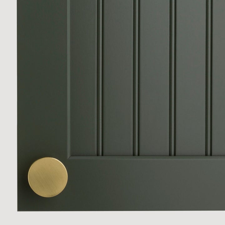 Close-up of a dark vertical paneled cabinet door with a round brass knob, showcasing sophisticated kitchen decor
